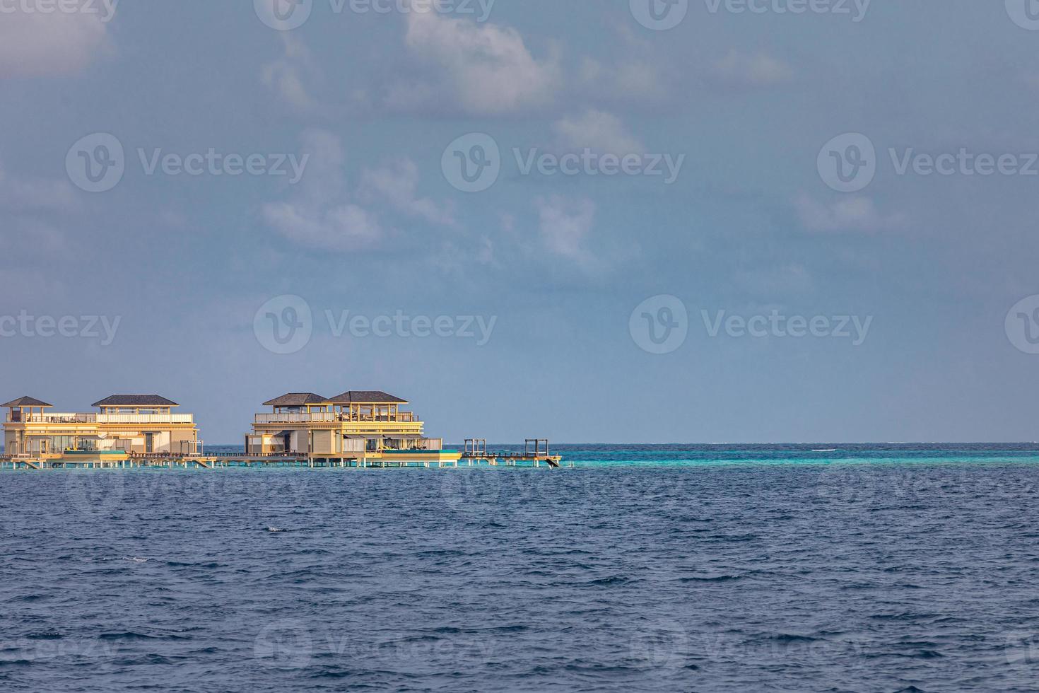 Water villas resort. Maldives Island, Indian Ocean. View from boat, exotic luxury over water bungalows. Summer travel and tourism concept, architecture elements on water photo