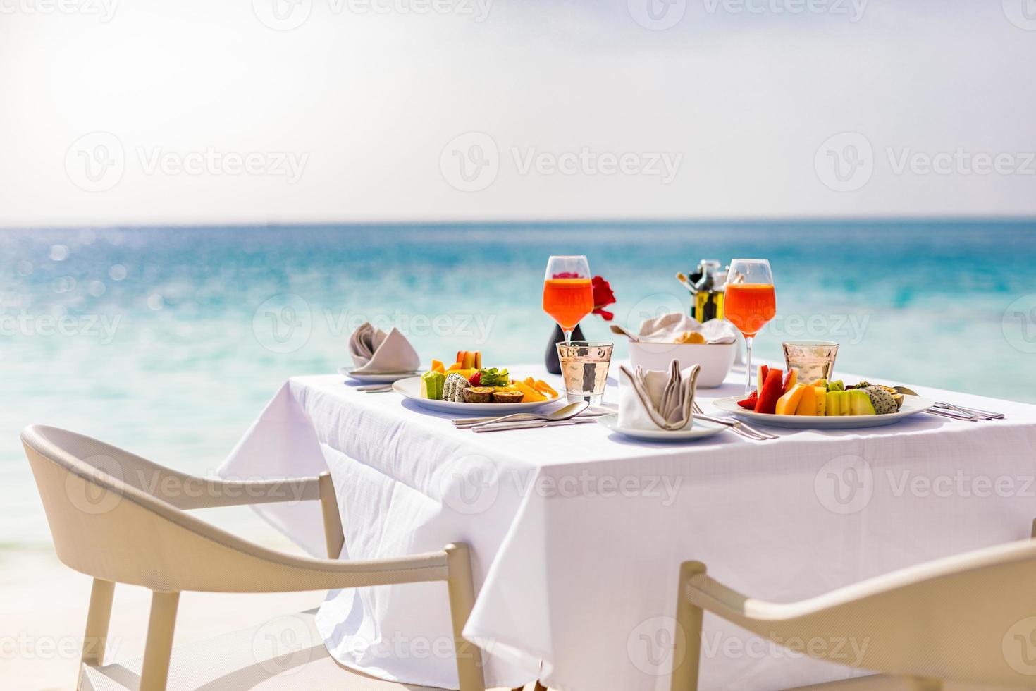 Fresh breakfast in a beautiful location with sea views. Luxury summer vacation or honeymoon destination. Table with gourmet delicious food near the sea with horizon. Beautiful summer breakfast setting photo