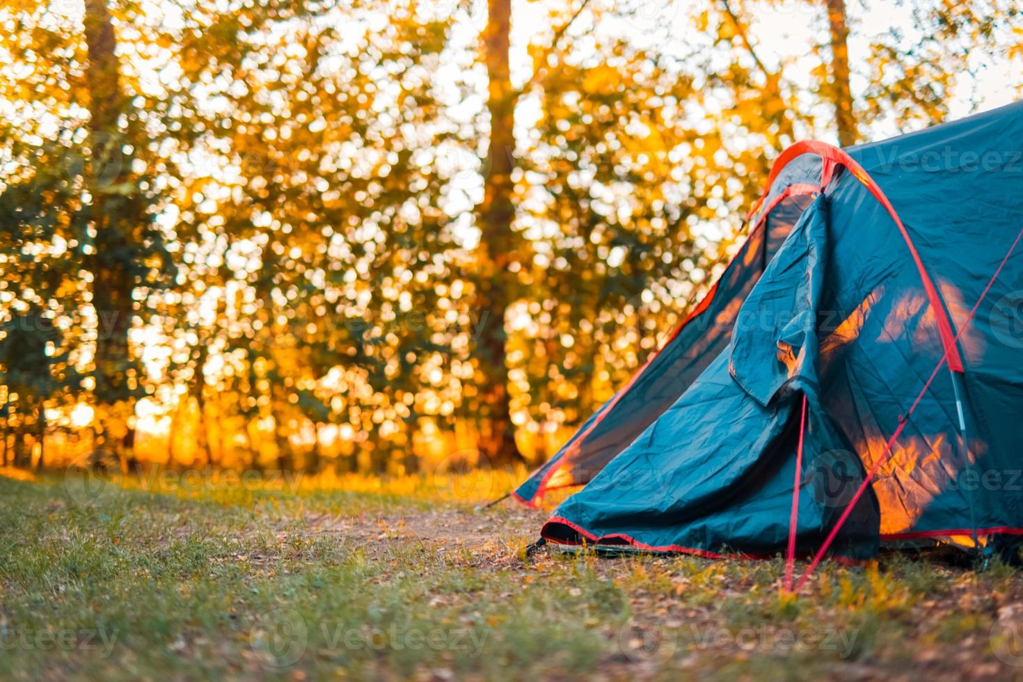 Camping tent in the forest with sunset and beautiful blurred nature scenery. Trees and sun rays in summer spring park. Hiking as recreational activity, outdoor nature forest scene photo