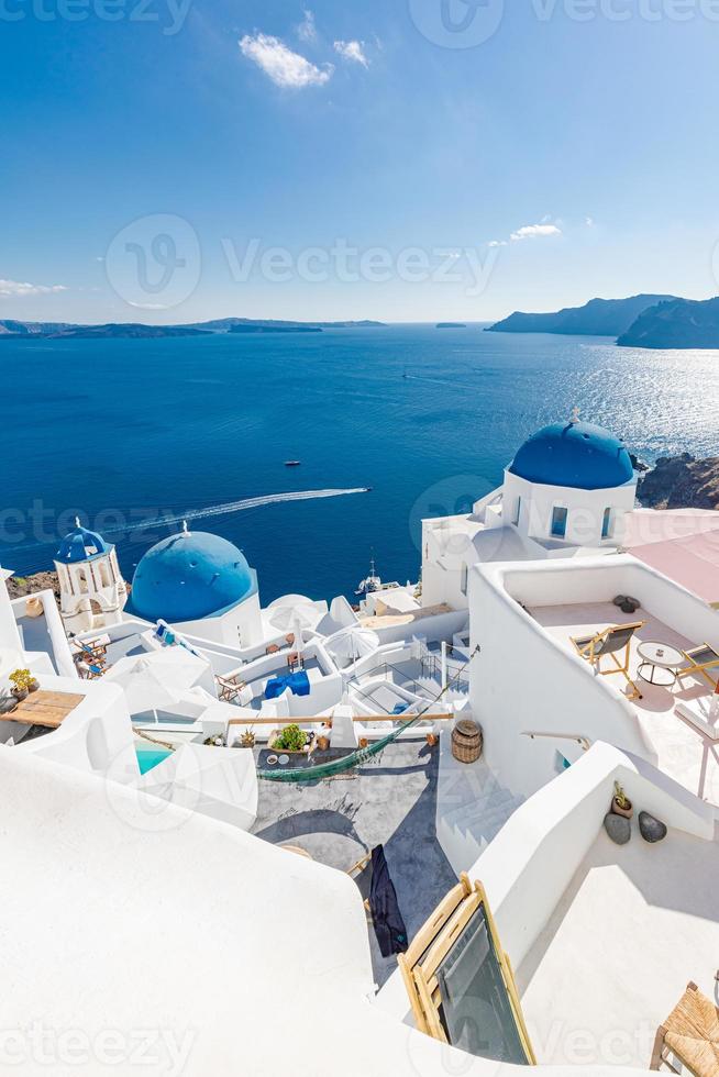 Beautiful Santorini, Oia village panorama. Summer travel and vacation background. Luxury panoramic scenery, perfect white architecture and blue sea, private pools, loungers. Luxury summer landscape photo