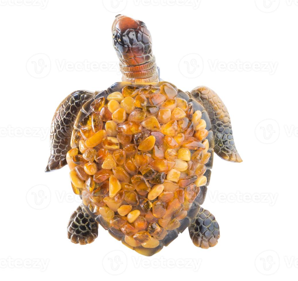 estatuilla de una tortuga sobre un fondo blanco con piedras de ámbar en el caparazón. vista desde arriba. foto