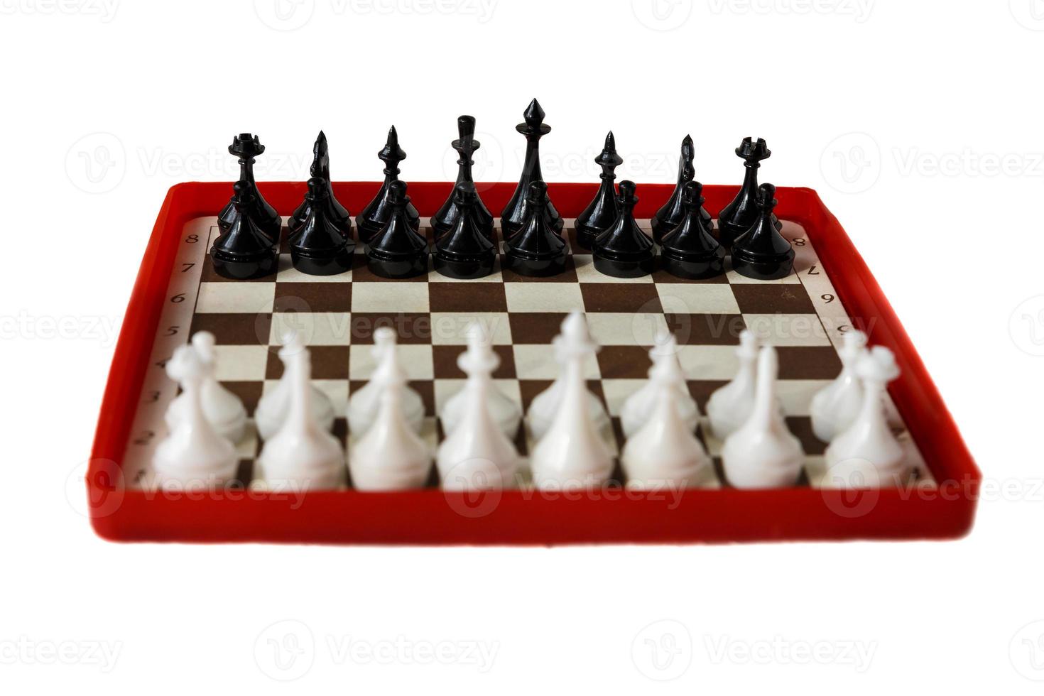 plastic chess board isolated on a white background. Travel chess. Selective focus. Focus on black pieces. photo