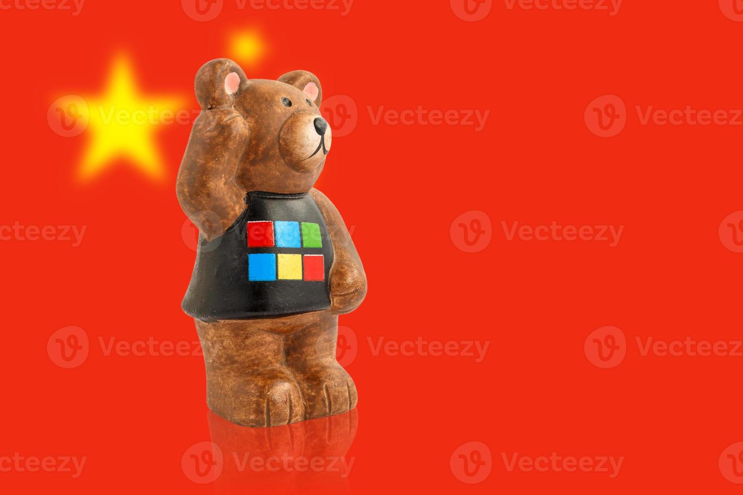 A figurine of a bear against the background of the flag of China. Blurred background. photo