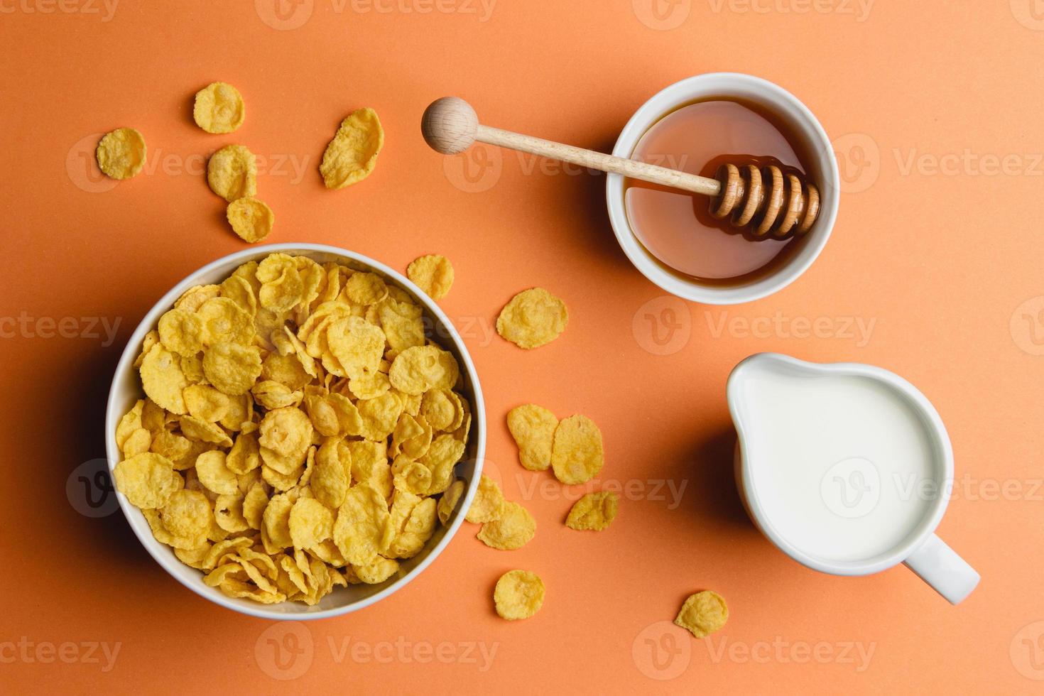 Corn flakes with milk and honey on orange background. photo