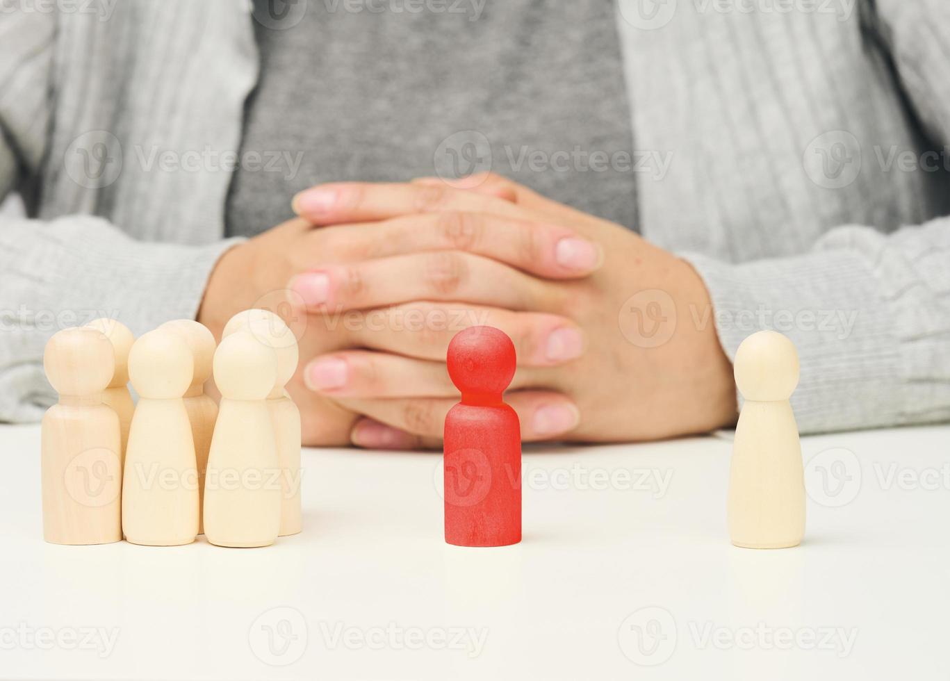 group of wooden figures, and one standing. Between them is a red wooden figurine of the negotiator man. Finding a compromise, discussion photo