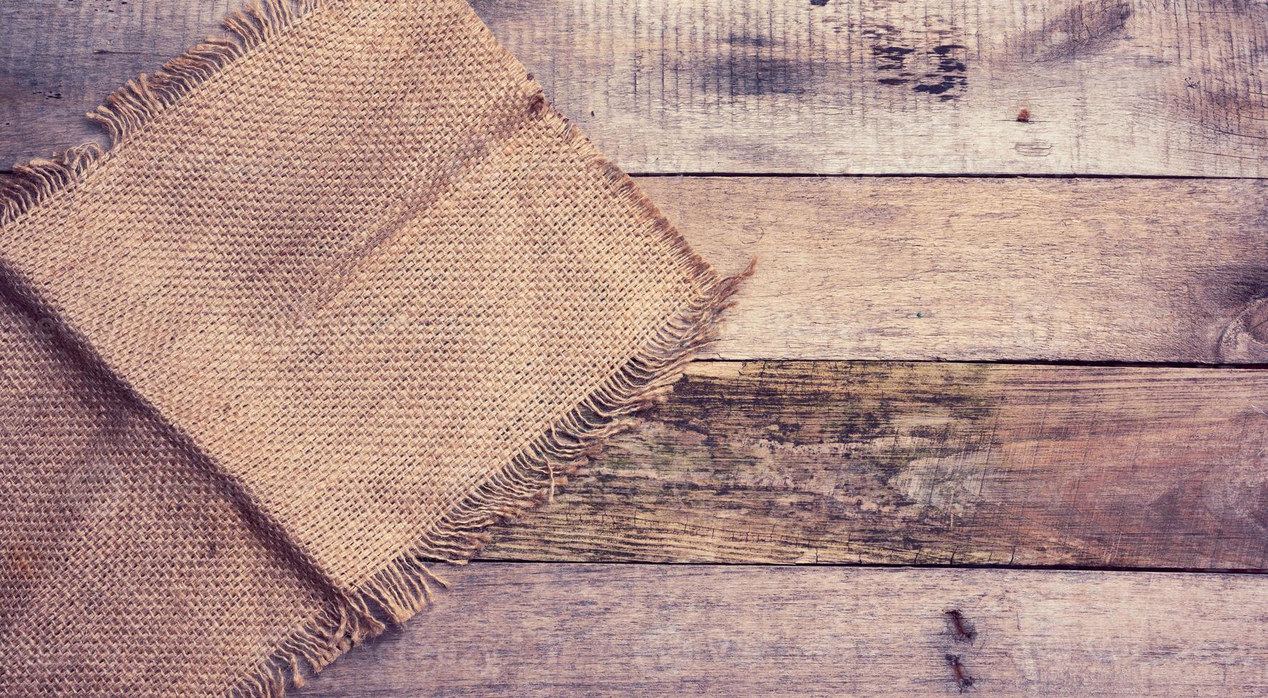 pedazo de arpillera con bordes rasgados sobre un fondo de tablas de madera gris foto