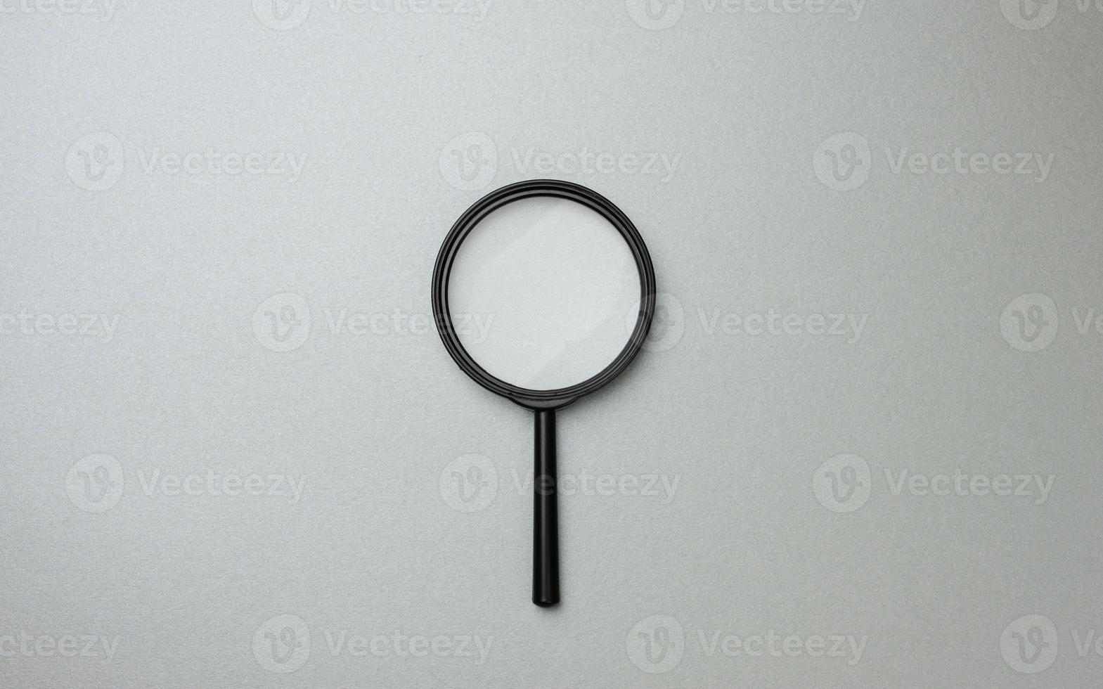 black magnifier on a gray background and question marks. The concept of uncertainty and the search for solutions photo