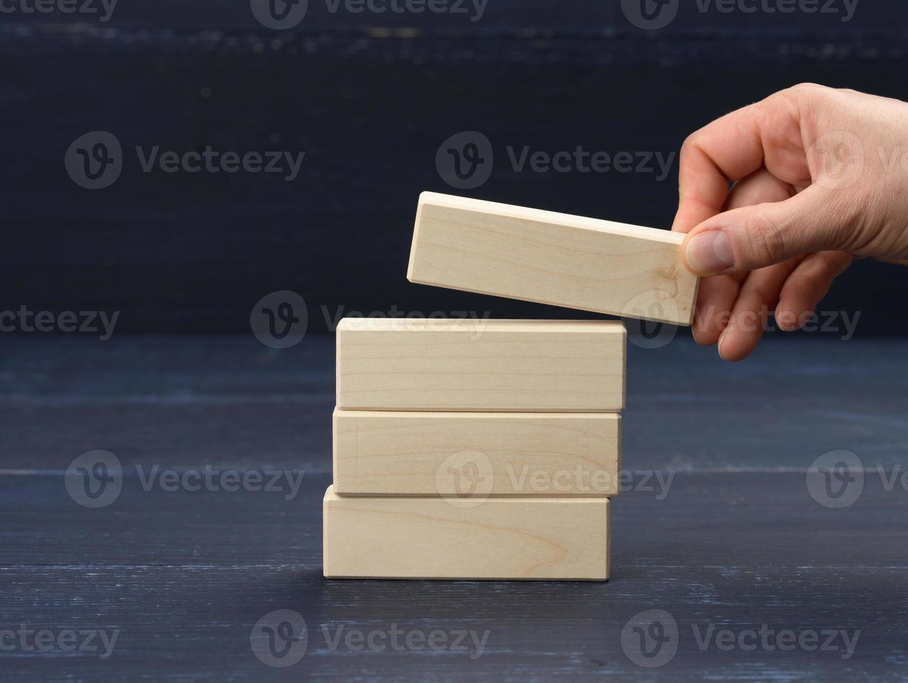 female hand puts wooden blocks on top of each other. Goal planning concept, new knowledge, strategy photo