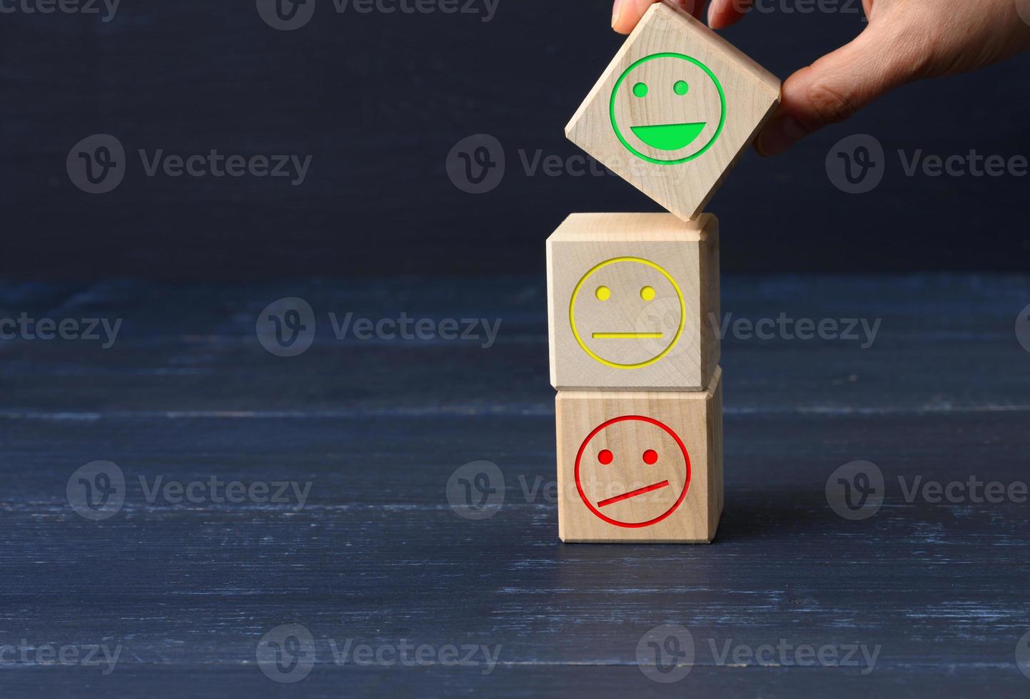 wooden blocks with different emotions from smile to sadness and a woman's hand. concept for assessing the quality of a product or service photo