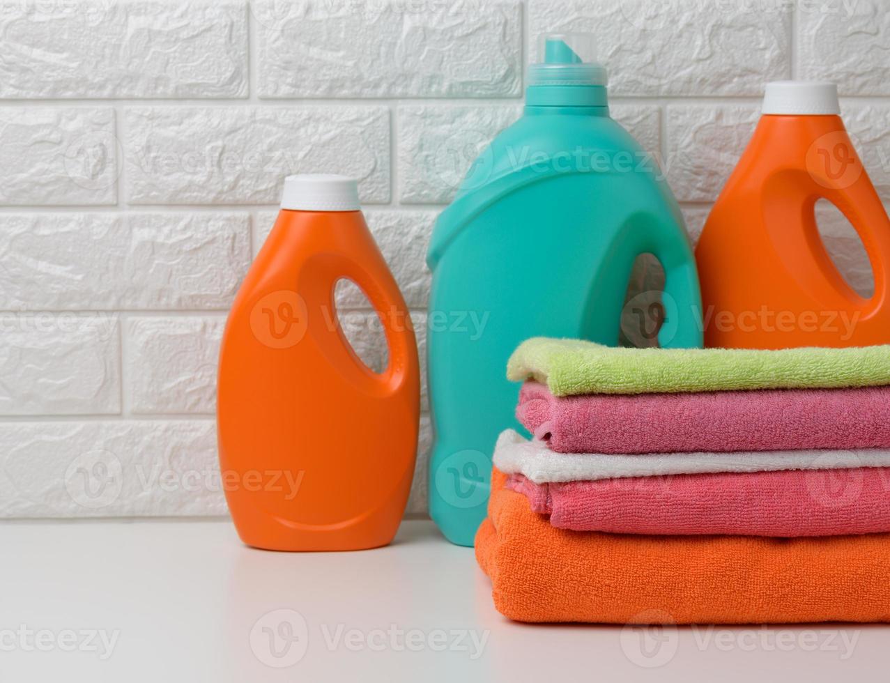 botellas de plástico con detergente líquido y toallas dobladas en un estante blanco. interior del baño foto