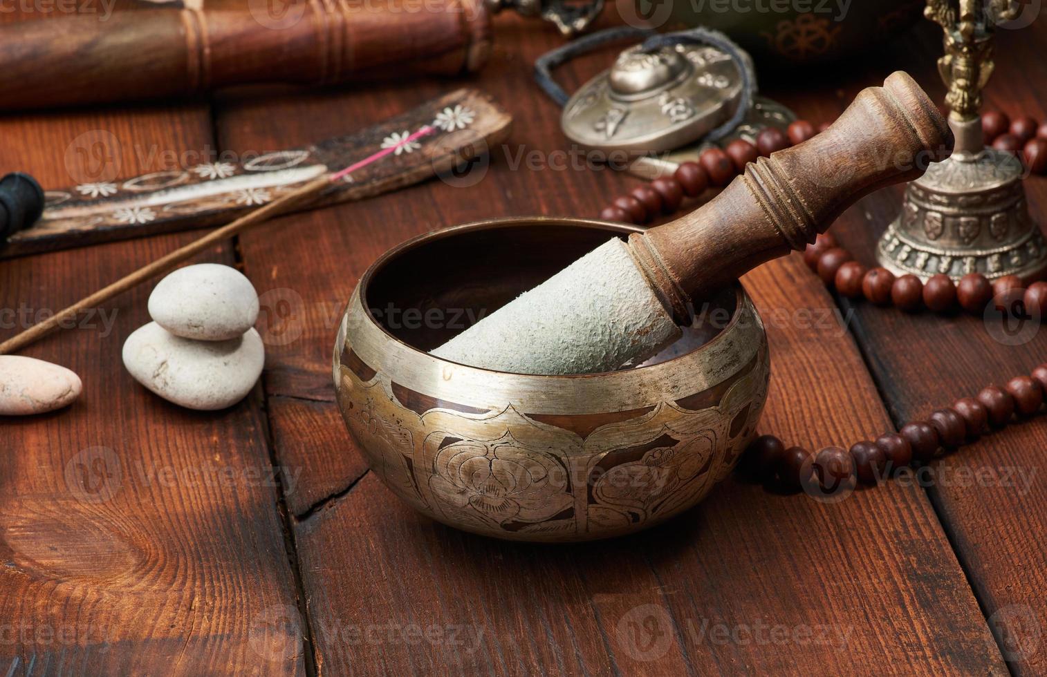 Cuenco tibetano de cobre cantando con una chapaleta de madera, objetos para la meditación y la medicina alternativa. sumergirse en un trance foto