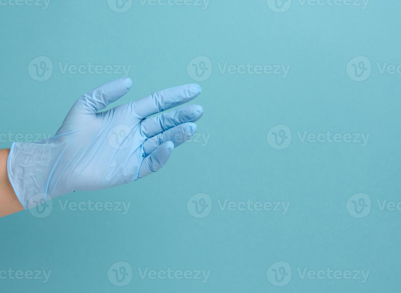 la mano del médico en un guante médico azul sostiene un objeto sobre un fondo azul foto