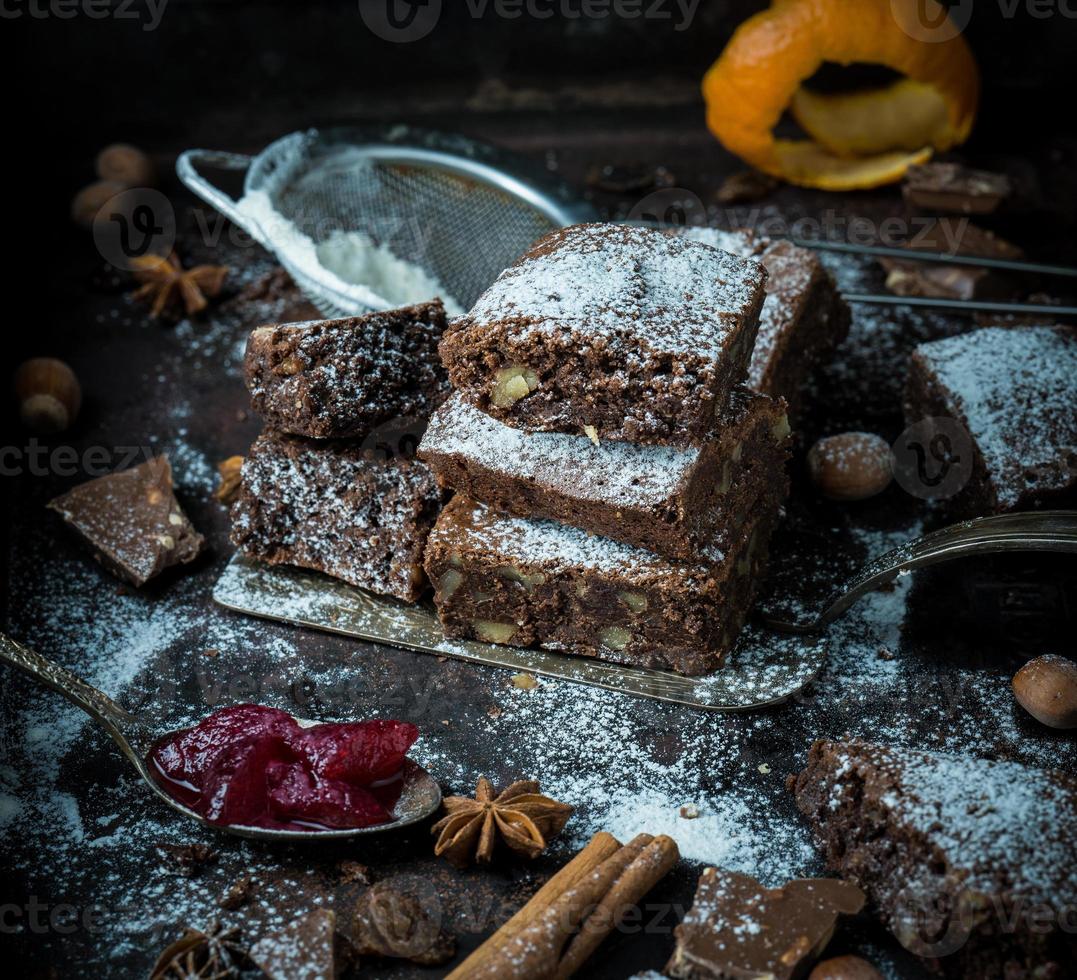 cuadrados de brownie espolvoreados con azúcar sobre una mesa negra foto