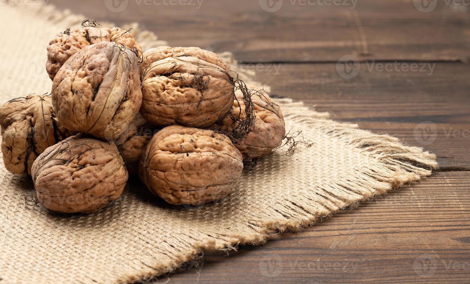 montón de nueces con cáscara en una mesa de madera marrón, cosecha de otoño foto