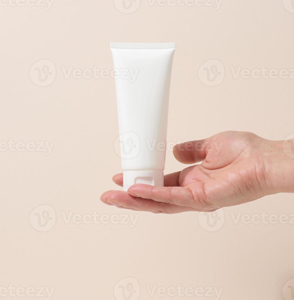 female hand holds empty white plastic tubes for cosmetics. Packaging for cream, gel, serum, advertising and product promotion, mock up photo