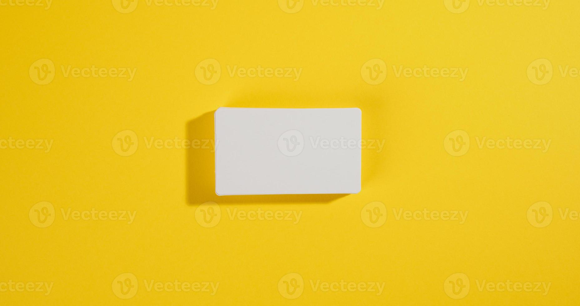 una pila de tarjetas de visita rectangulares blancas sobre un fondo amarillo, marca de empresa, dirección foto