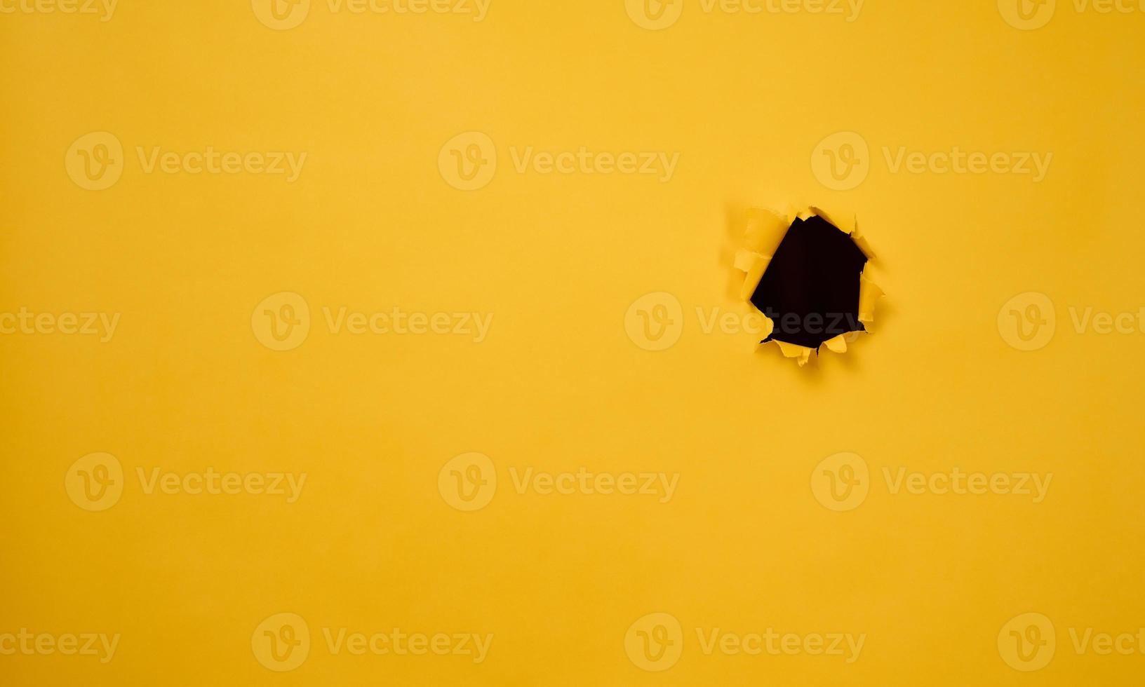 agujero con bordes rasgados en papel amarillo, fotograma completo. copie el espacio foto