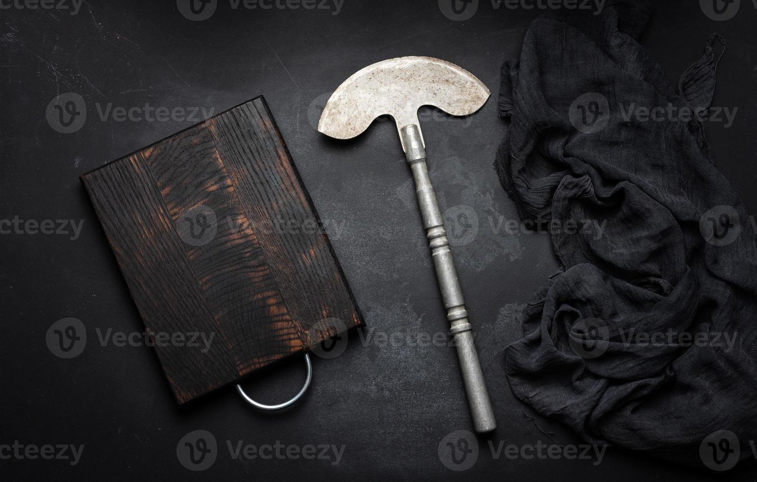 Rectangular empty wooden cutting board and kitchen knife on black table with gauze napkin, top view photo