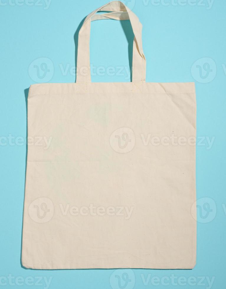 empty linen eco friendly beige canvas tote bag for branding on blue background. Clear reusable bag for groceries, mock up photo