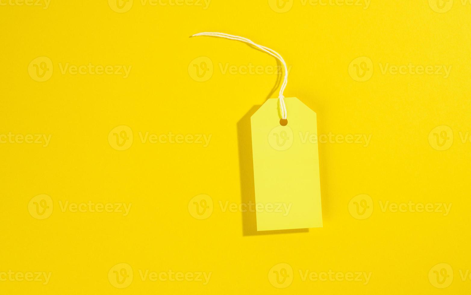 blank rectangular paper yellow price tag with white rope on yellow background photo