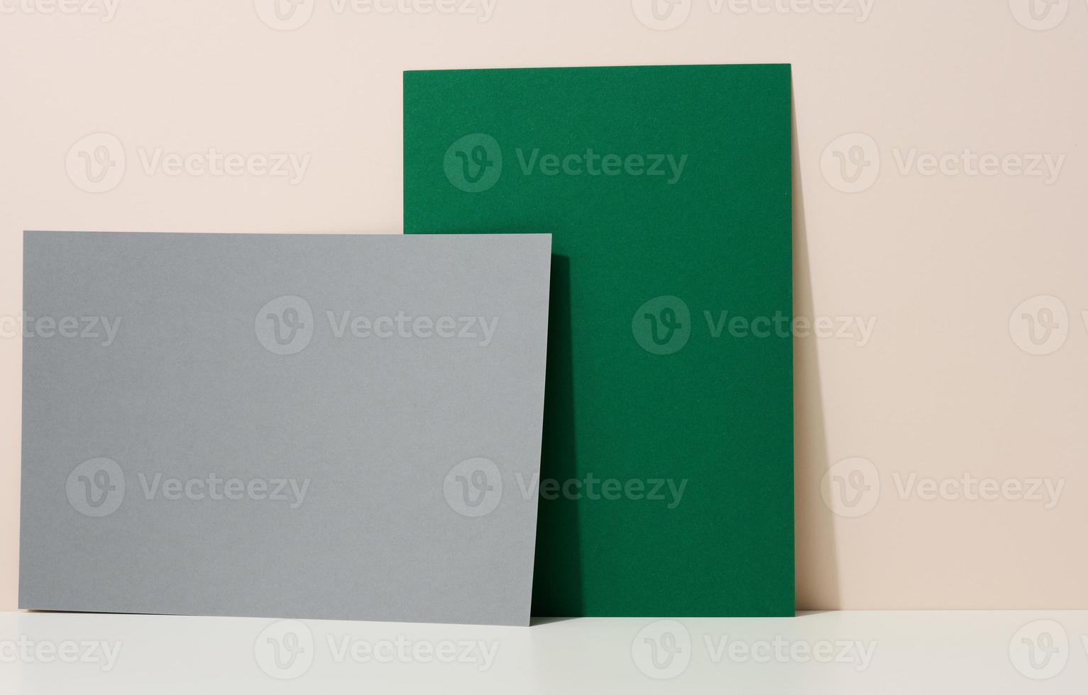 hoja de papel de cartón verde y gris en blanco con sombra en la mesa blanca. plantilla para volante, anuncio foto