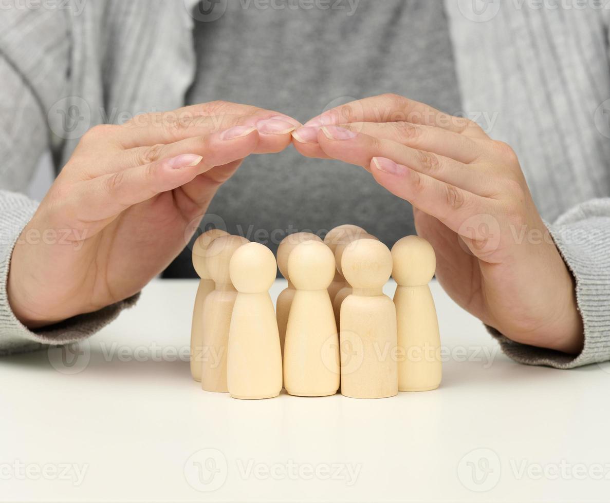 figurillas de madera de hombres, una familia custodiada por dos manos femeninas. ayuda, seguro de vida foto