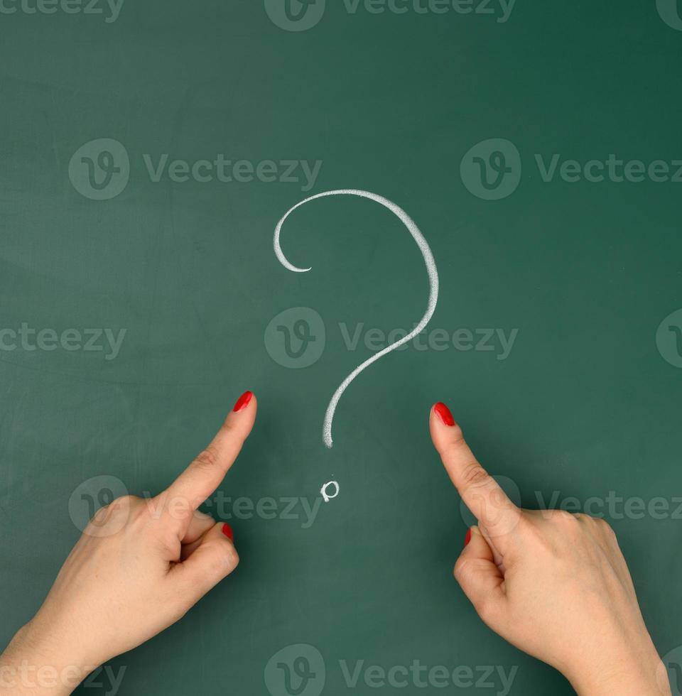 question mark drawn in white chalk and female hands point a finger at it photo