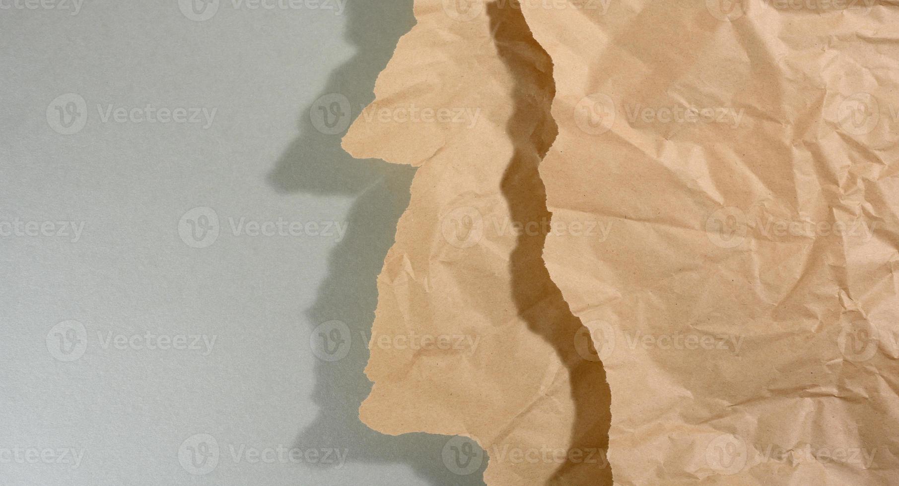 mint brown piece of paper with torn edges and shadow on gray background. Abstract creative backdrop for designer photo