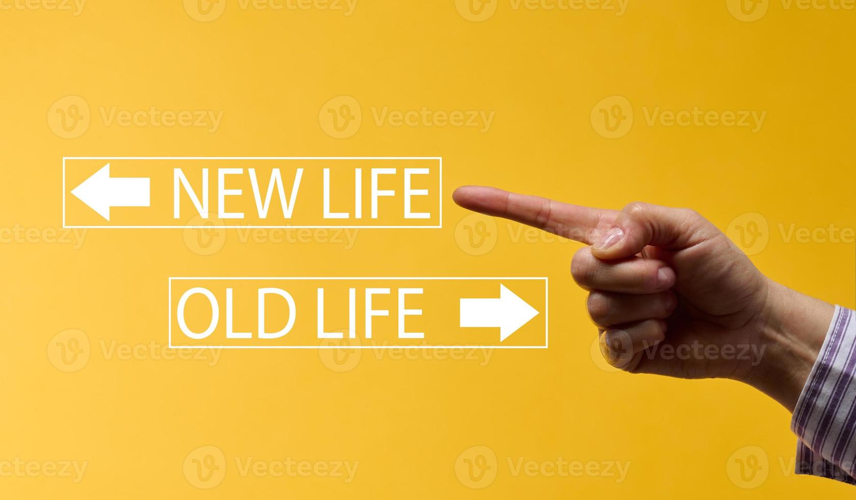 a female hand points to a plate with the inscription new life on a yellow background. The concept of starting a new year, business development, personal growth, success photo