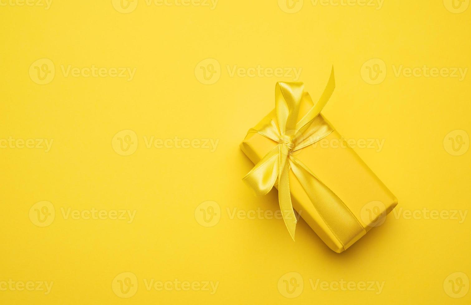 caja rectangular amarilla con un regalo envuelto en papel amarillo foto