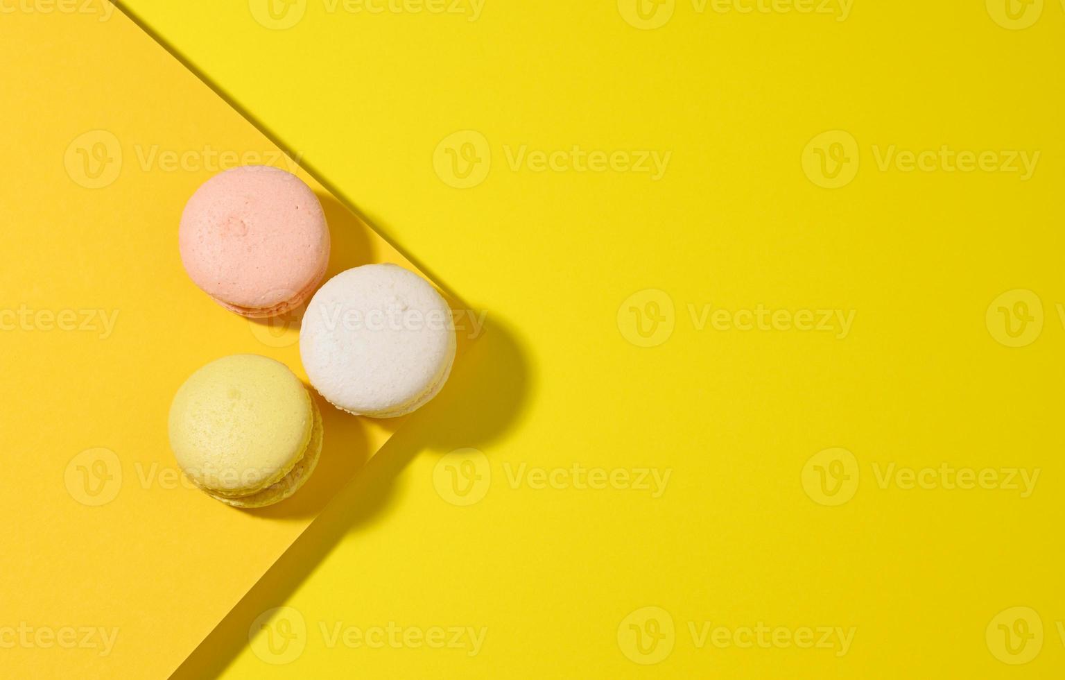 macarons multicolores redondos sobre un fondo amarillo con una sombra sobre un fondo amarillo foto