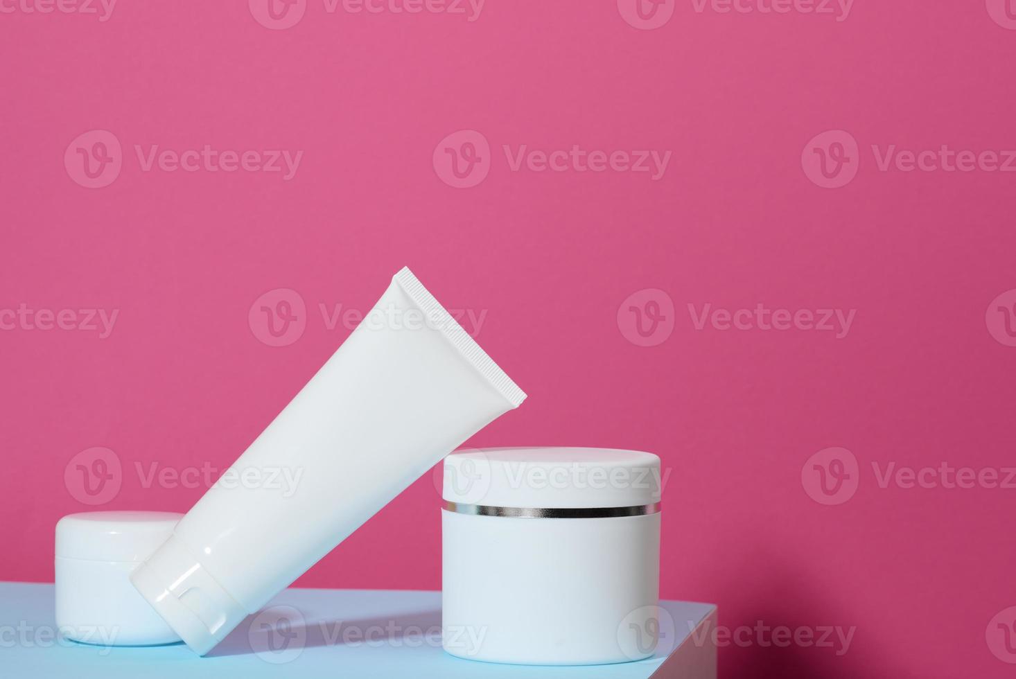 frasco y tubos de plástico blancos vacíos para cosméticos sobre un fondo rosa. envases para crema, gel, suero, publicidad y promoción de productos foto