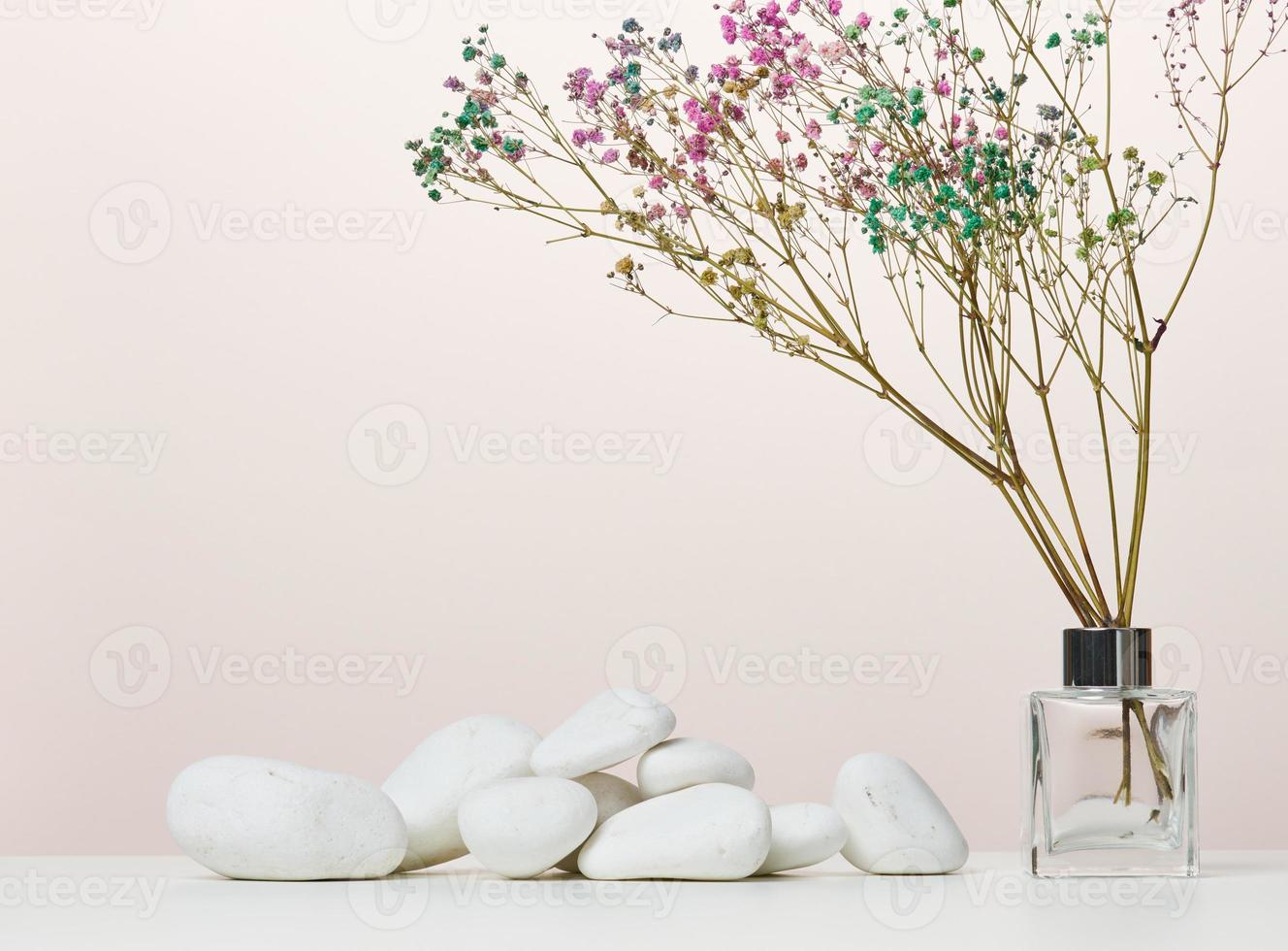 Bouquet of dried flowers in a glass transparent vase on a white table photo