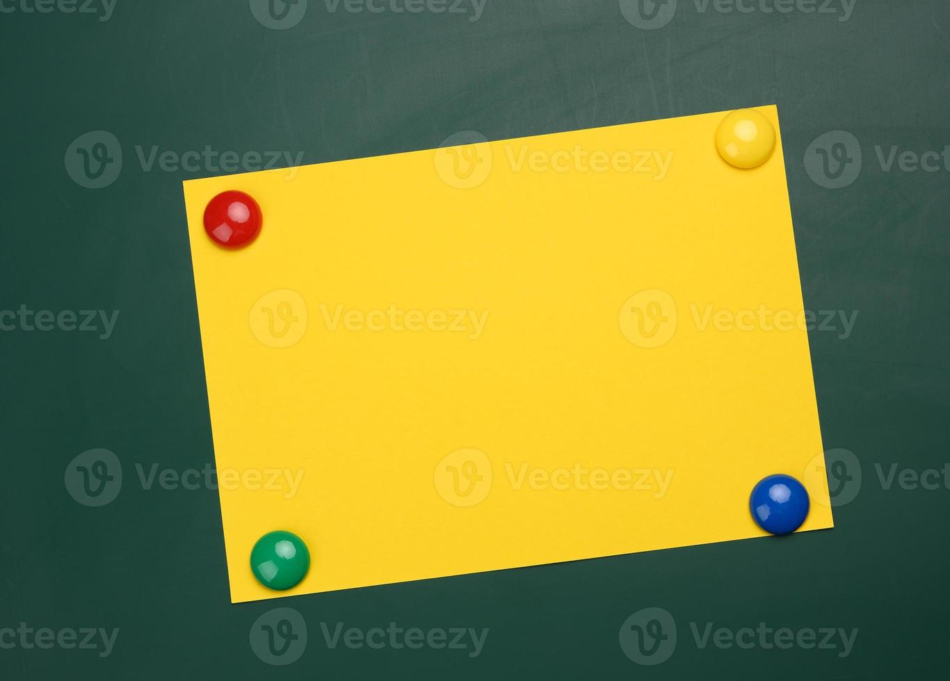 blank yellow sheet of A4 paper hanging on a green magnetic board photo