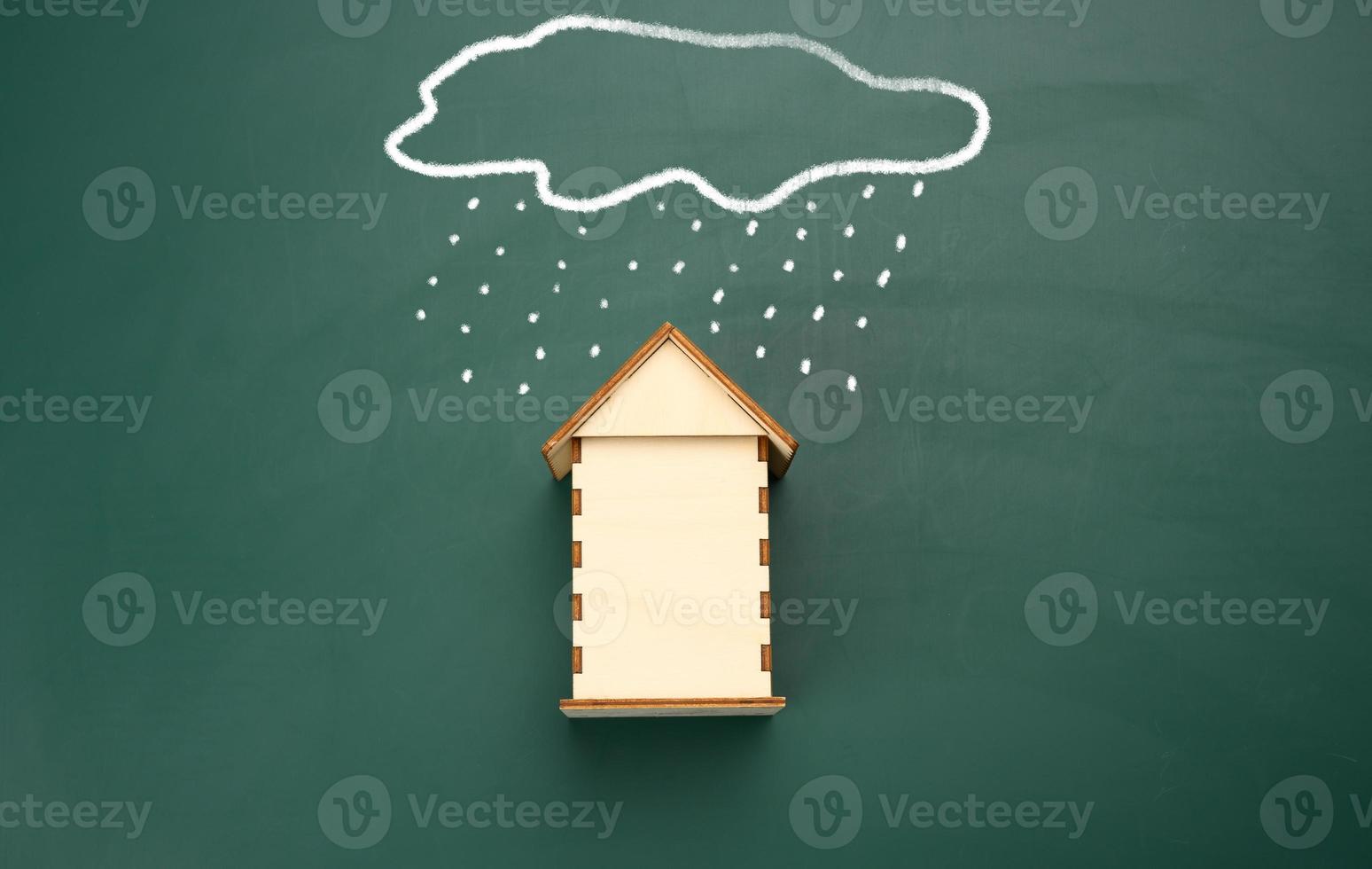 a wooden house and a drawn cloud with rain with white chalk on a green chalk board. photo