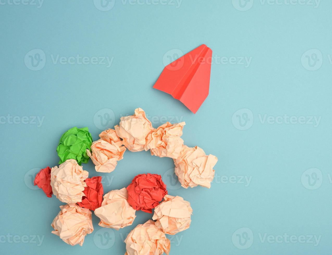 red paper airplane and crumpled paper balls on a blue background, top view. photo