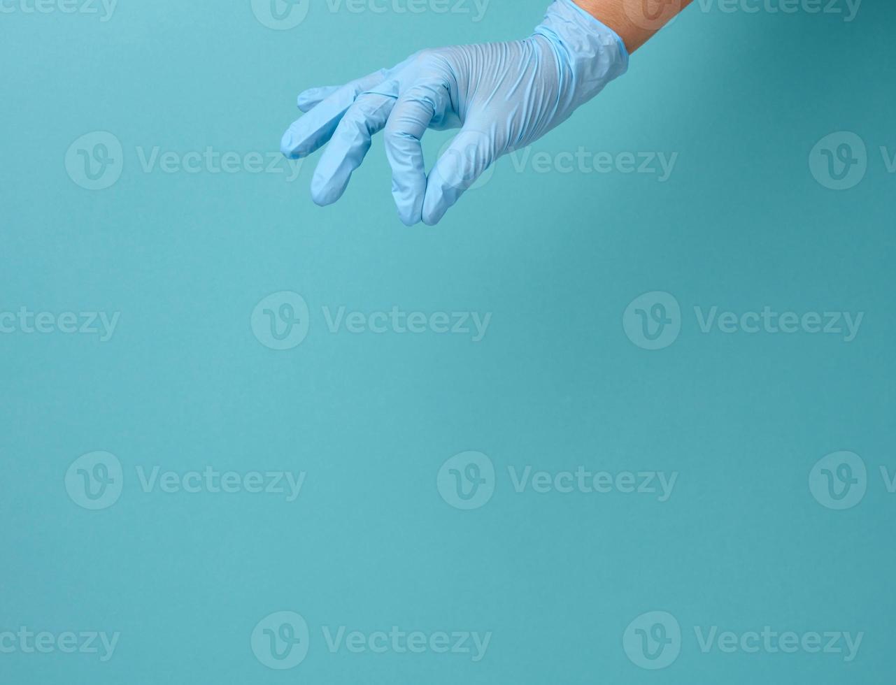 Doctor's hand in a blue medical glove holds an object on a blue background photo