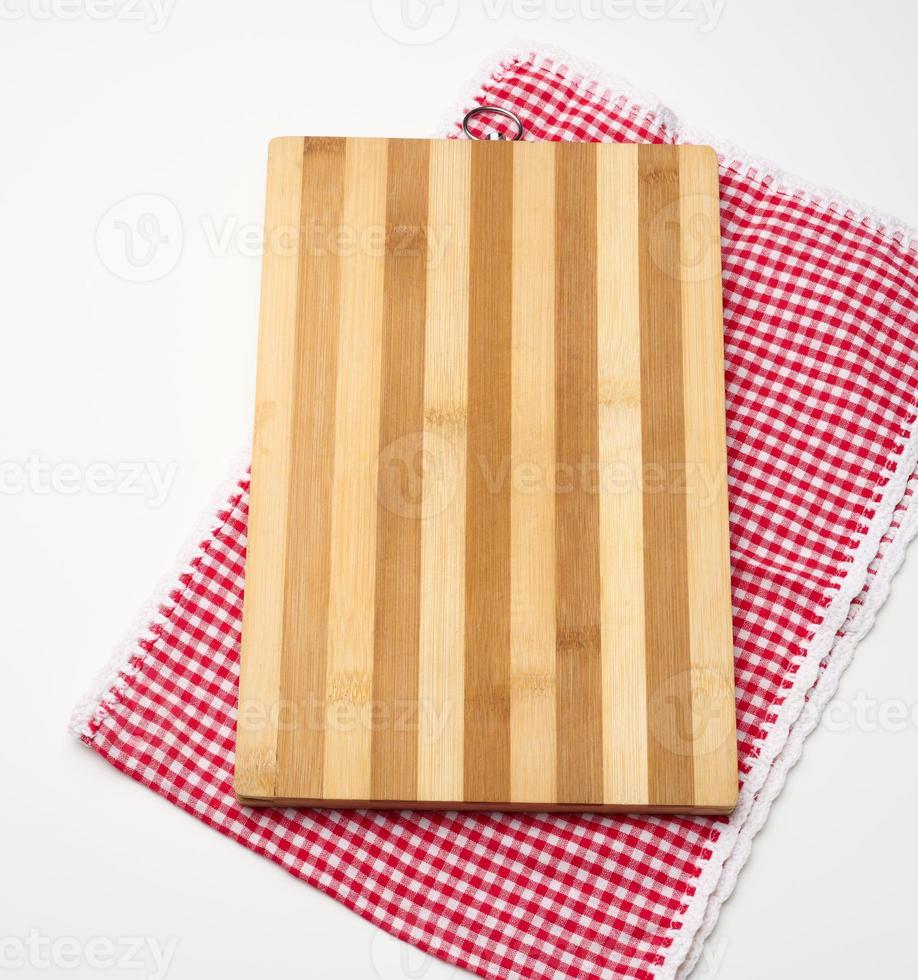 empty rectangular wooden kitchen cutting board and red towel in a white cage on a white table, top view photo