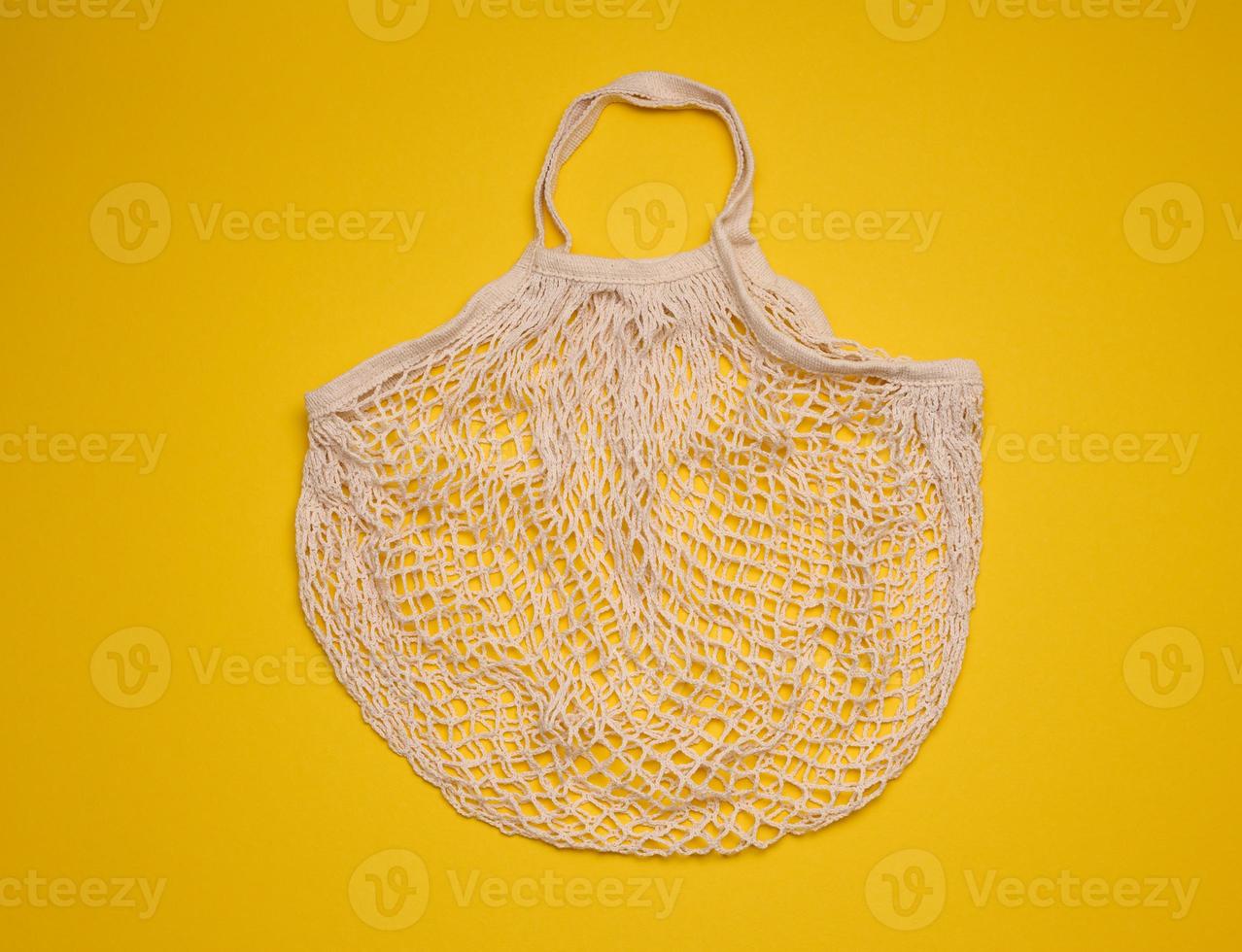 empty cotton reusable bag on yellow background. Refusal of plastic, recyclable waste photo