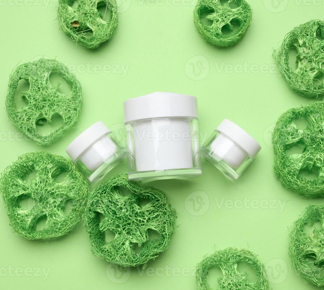 empty white jar for cosmetics on a green background. Packaging for cream, gel, serum, advertising and product promotion. Mock up, top view photo