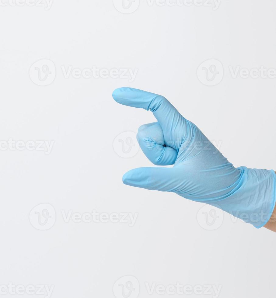 Doctor's hand in a blue medical glove holds an object on a white background. Copy space, hold any object photo