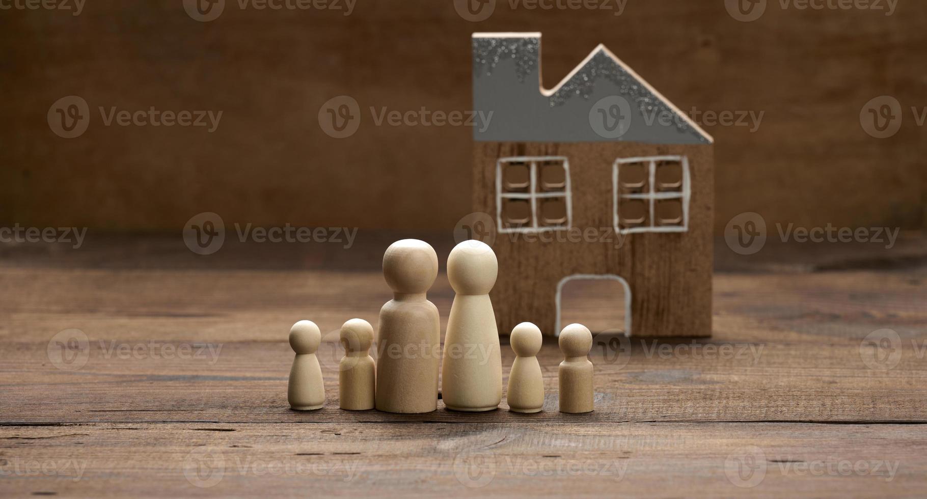 wooden family figurines, model house on a brown background. Real estate purchase, rental concept. Moving to new apartments photo