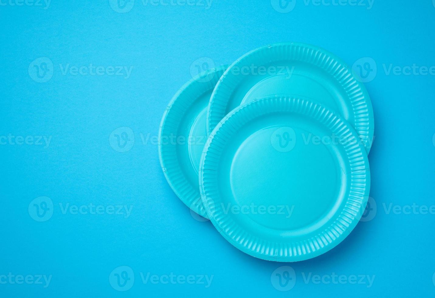 Empty white paper disposable plates on a bluen background, top view. The concept of rejection of plastic, environmental conservation photo