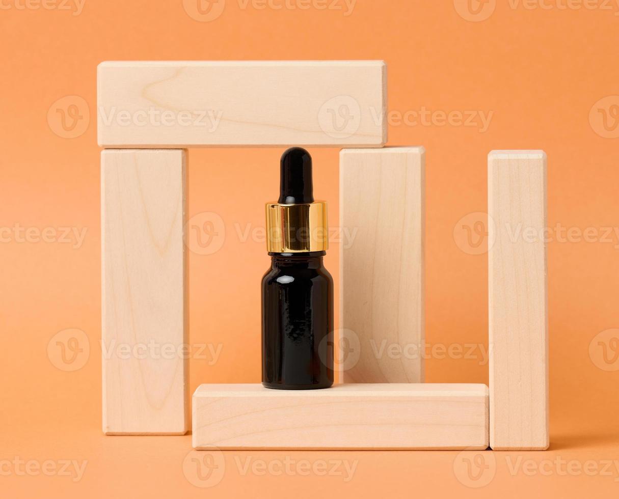 black glass bottle with a dropper for cosmetics on an orange background. Packaging for gel, serum, advertising and promotion. Natural organic products photo