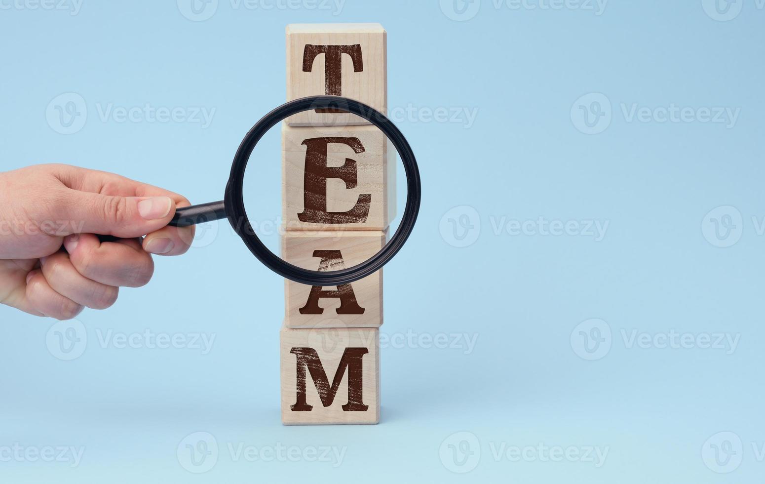 hand with a magnifying glass on a blue background. The concept of recruiting and finding talented employees photo