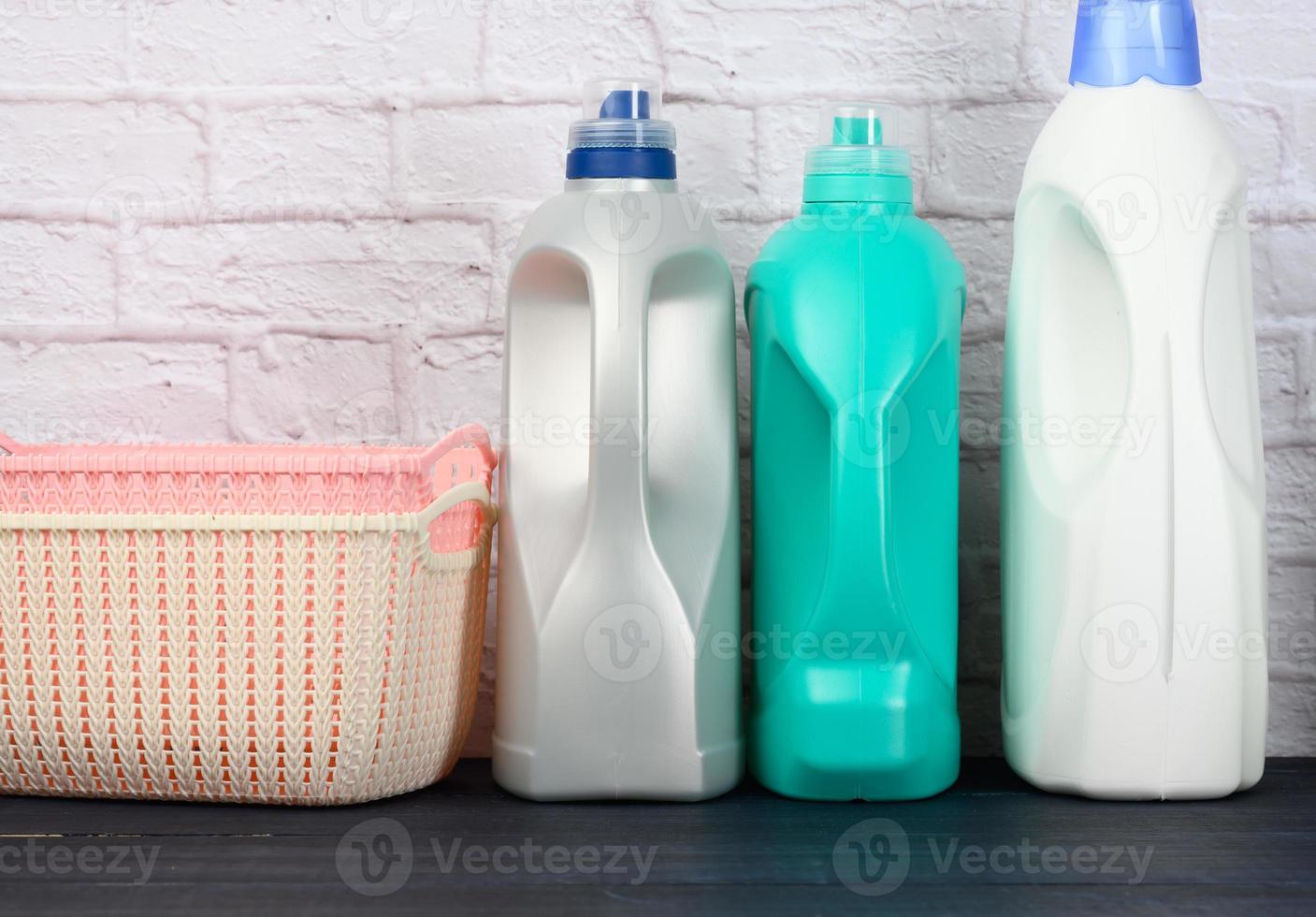 bottles with liquid detergent and plastic empty laundry baskets on a wooden blue table photo