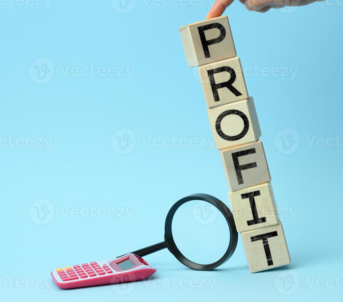 wooden cubes with the inscription benefit, calculator and magnifier on a blue background. The concept of maximum benefits from the deal, the best offer photo