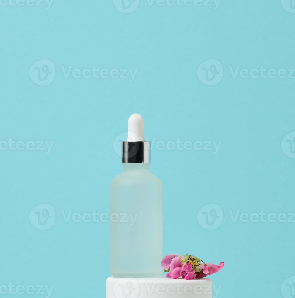 white glass bottle with pipette stands on a blue background. Cosmetics SPA branding. Packaging for gel, serum, advertising and product promotion, mock up photo