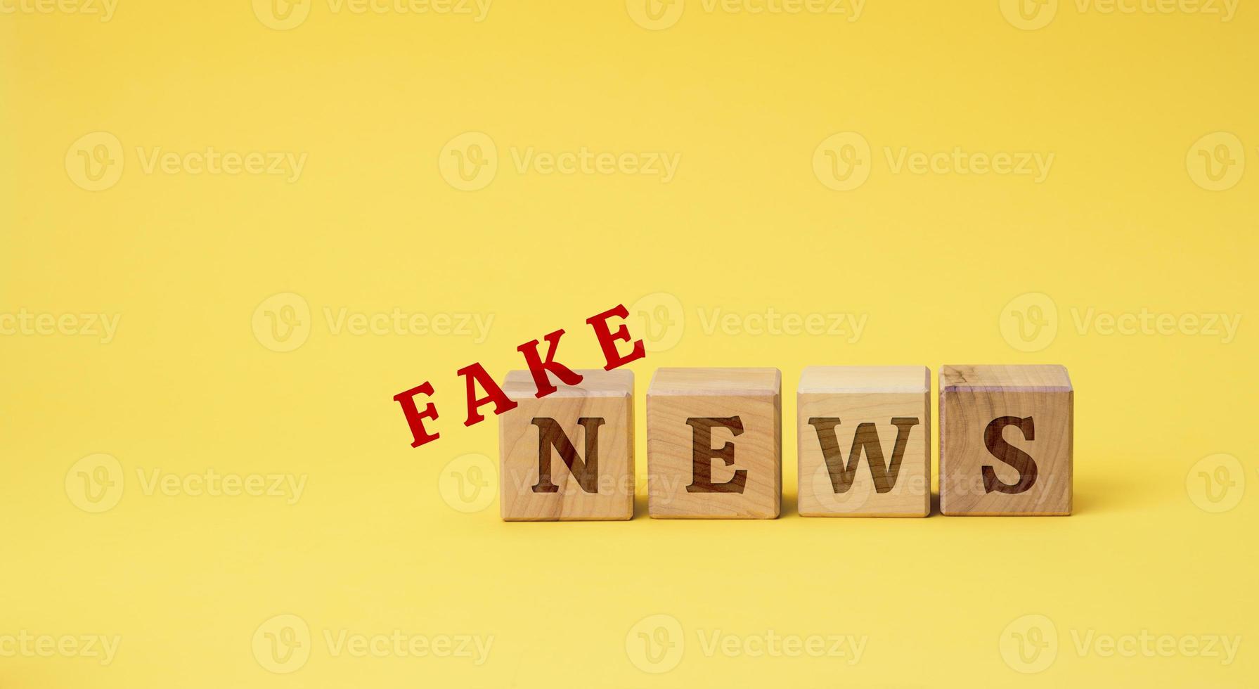 wooden cubes with the inscription false news on a yellow background. The concept of information hygiene, propaganda, debunking of myths and false information photo