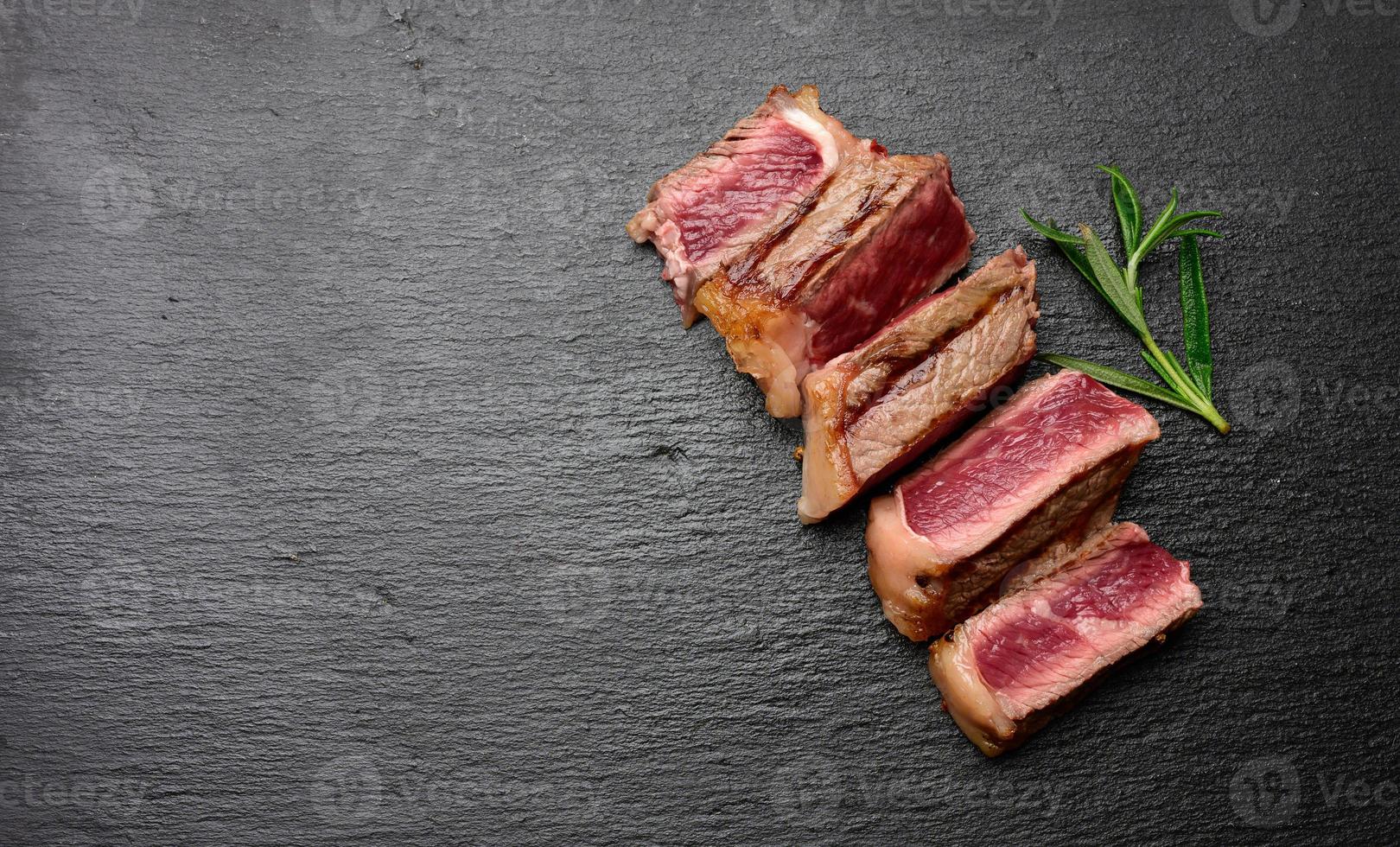 sliced fried beef steak New York on a black background, degree of doneness rare photo